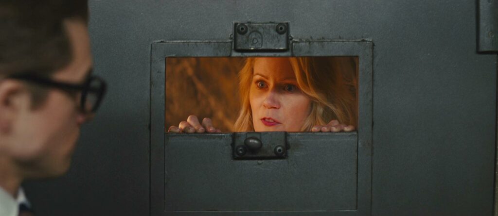 A woman talking a man from inside a closed room